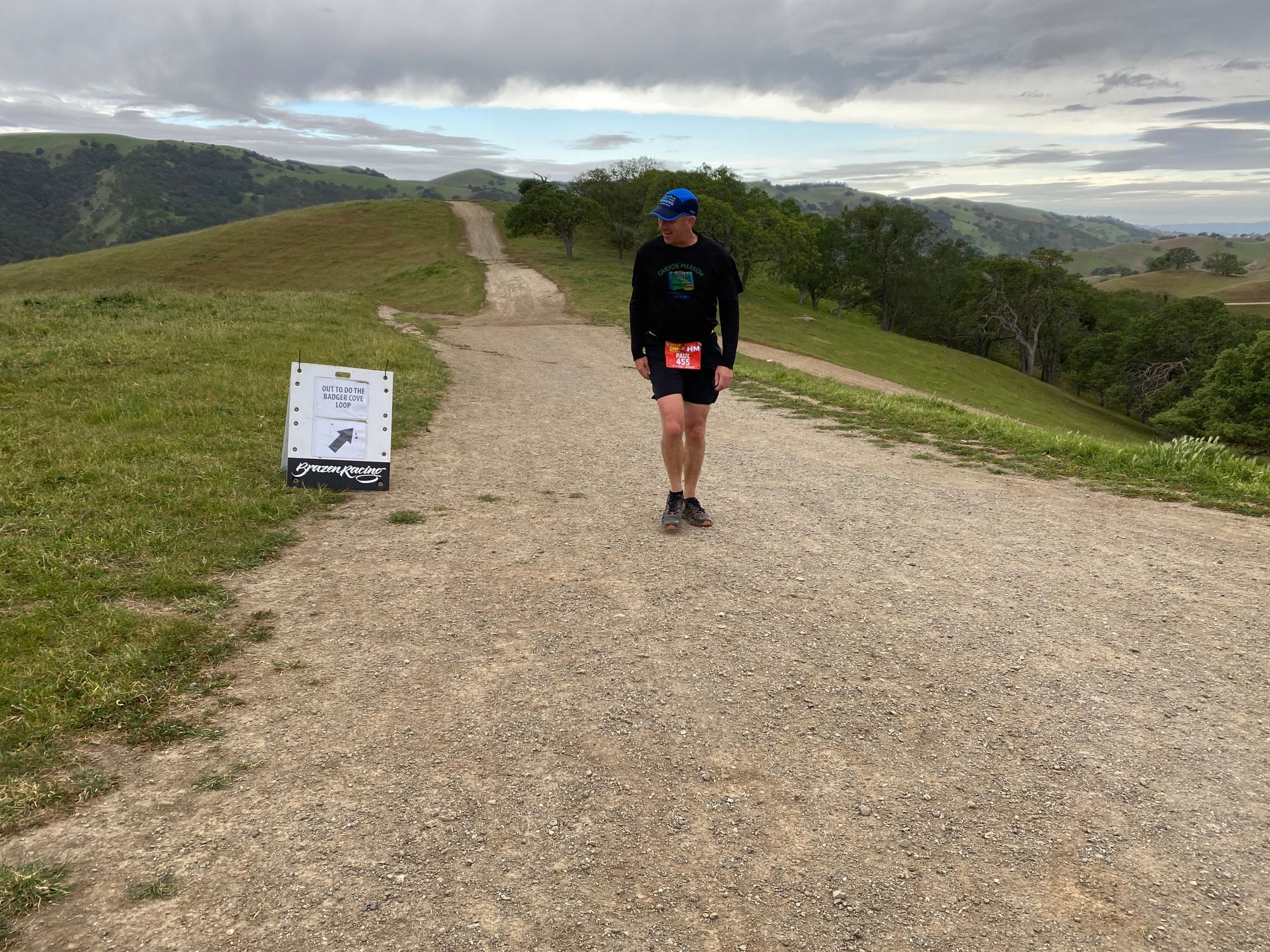 Paul walking down a dirt trail looking at a direction sign.